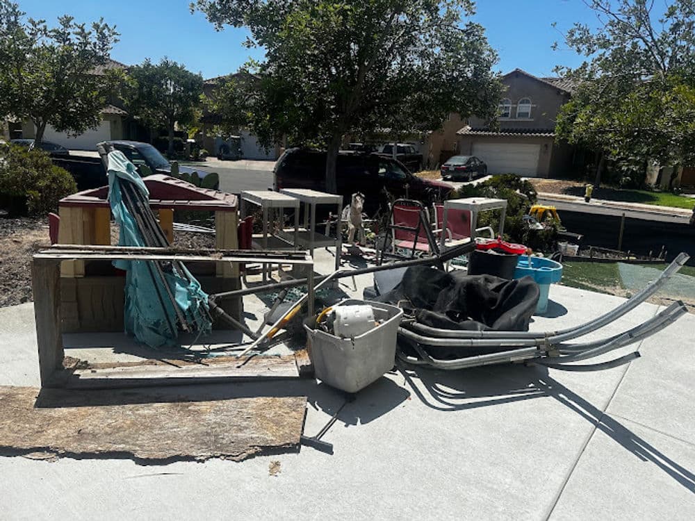 Discarded furniture and construction debris in a residential outdoor area on a sunny day.