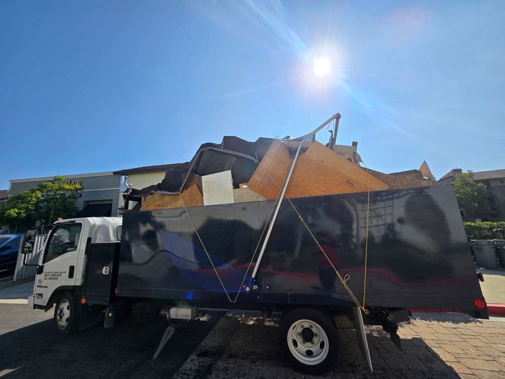 Pickup truck loaded with construction debris under a bright sun.