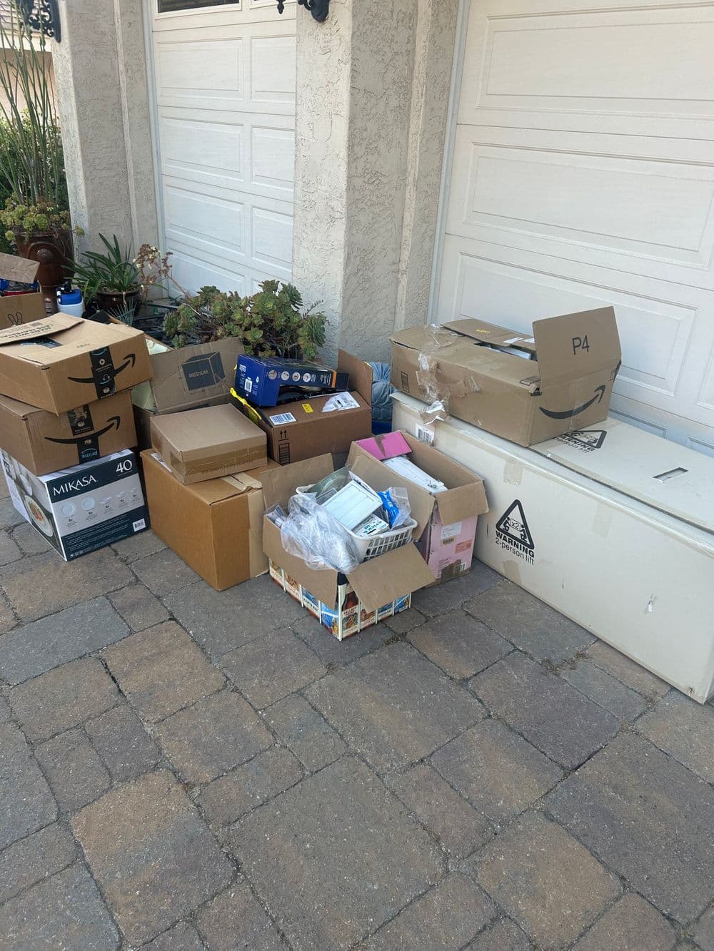 Pile of cardboard boxes and packaging materials stacked outside a garage door.