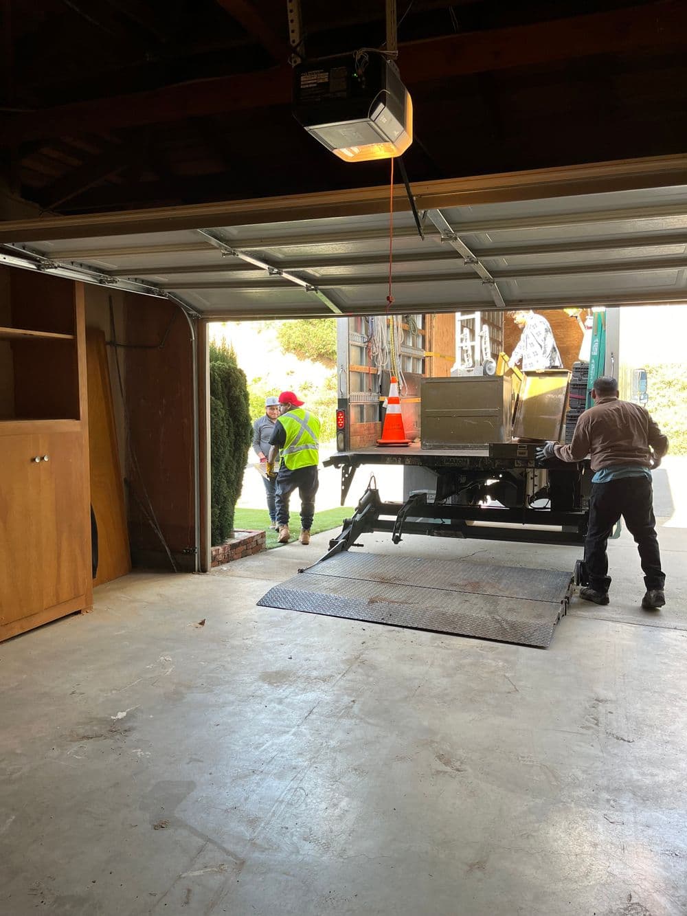 Two movers unloading a large item from a truck into a garage.