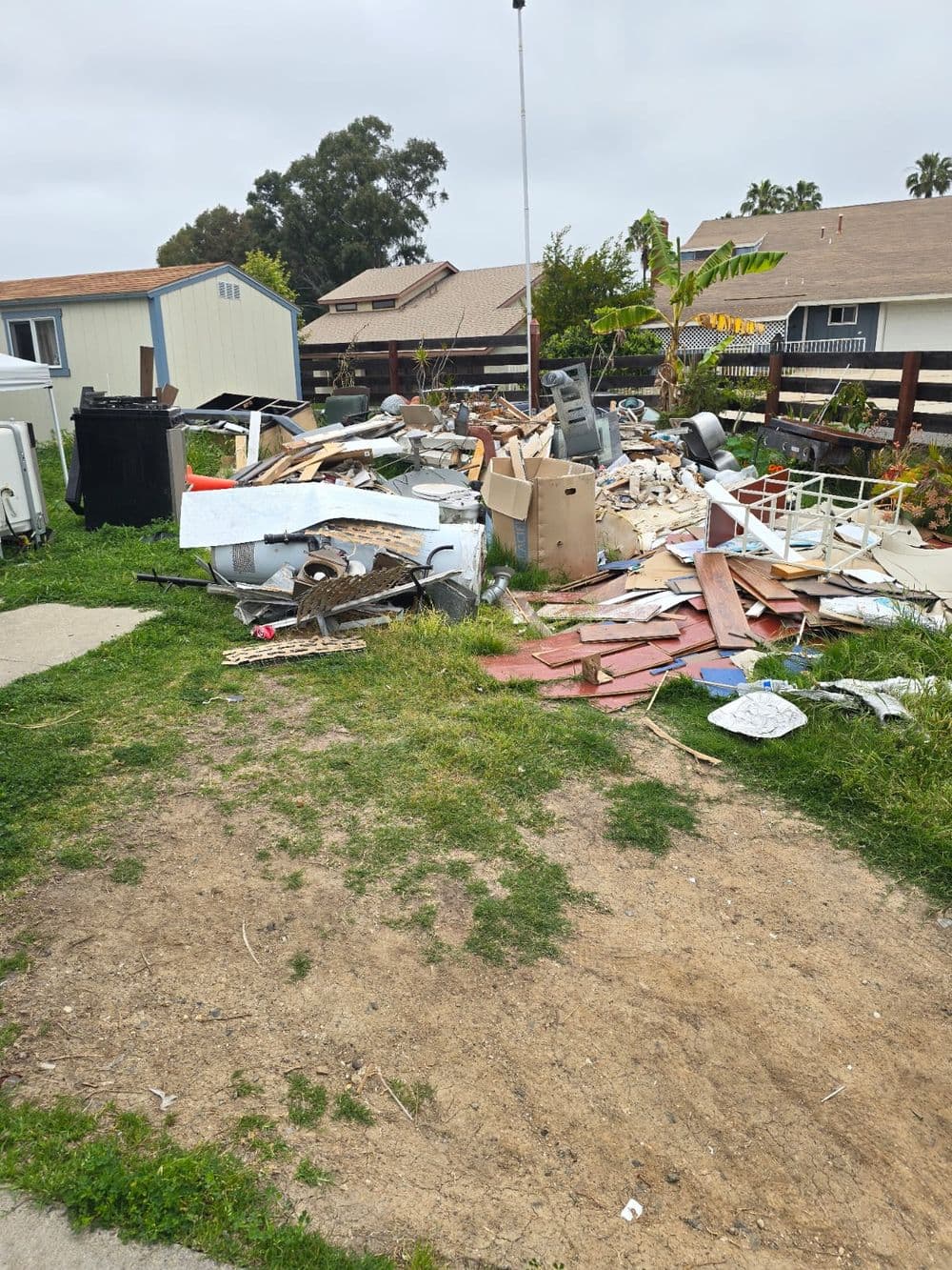 Piles of debris and discarded materials in a residential yard.