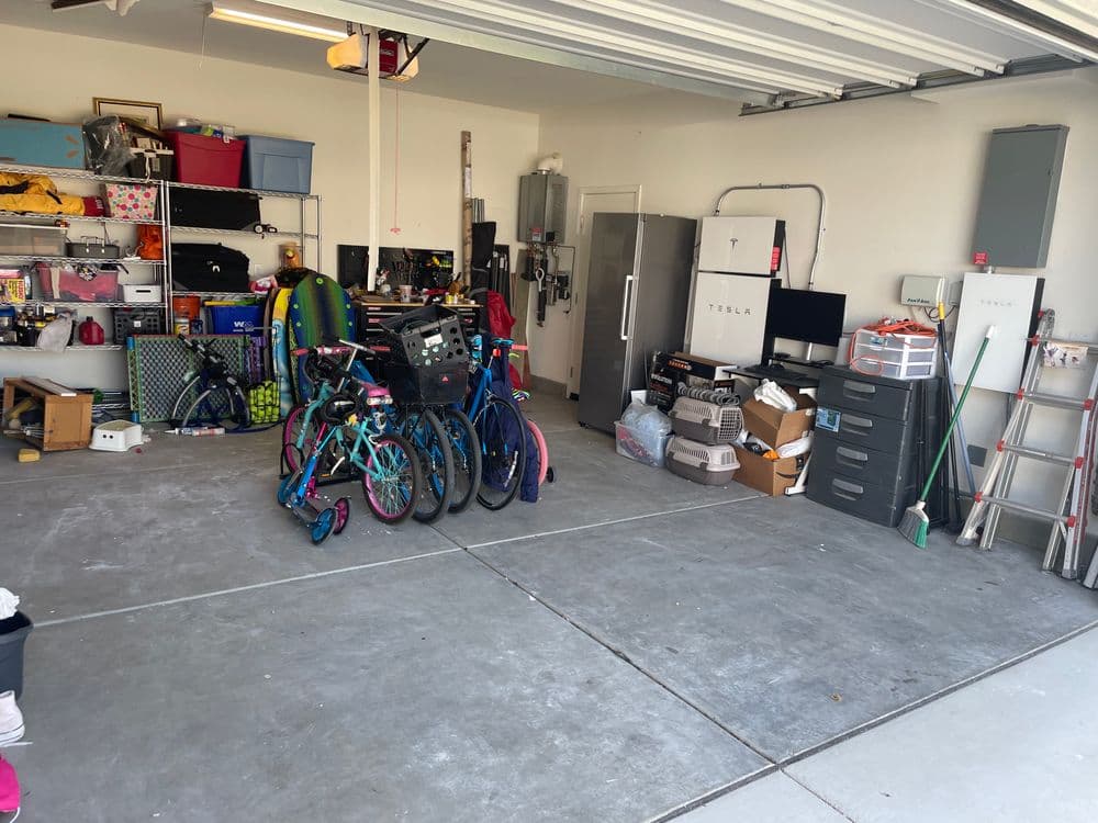 Organized garage with bicycles, storage bins, and a Tesla charging station visible.