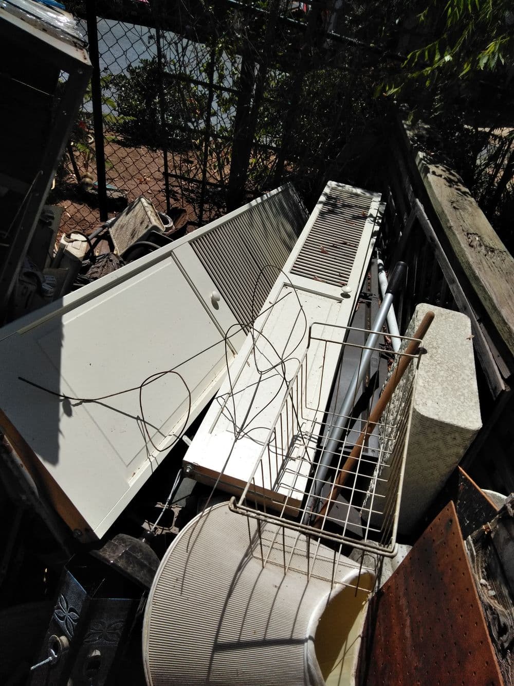Discarded furniture and appliances piled in a cluttered outdoor space.
