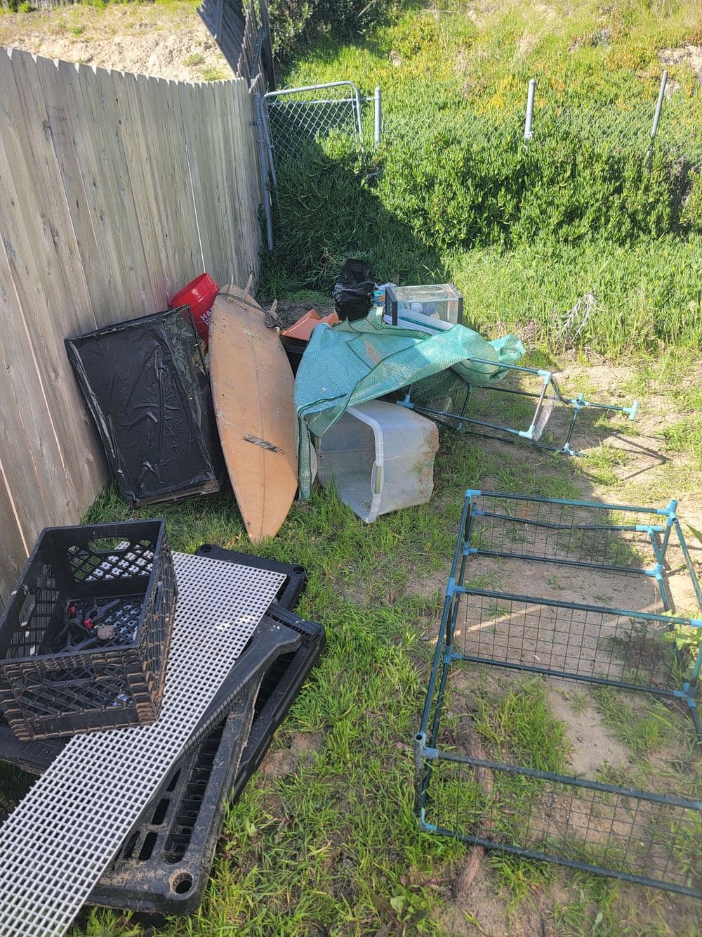 Cluttered backyard with various discarded items, including a tarp, crates, and furniture.